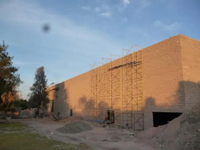 Nave de block aparente con andamios en fachada