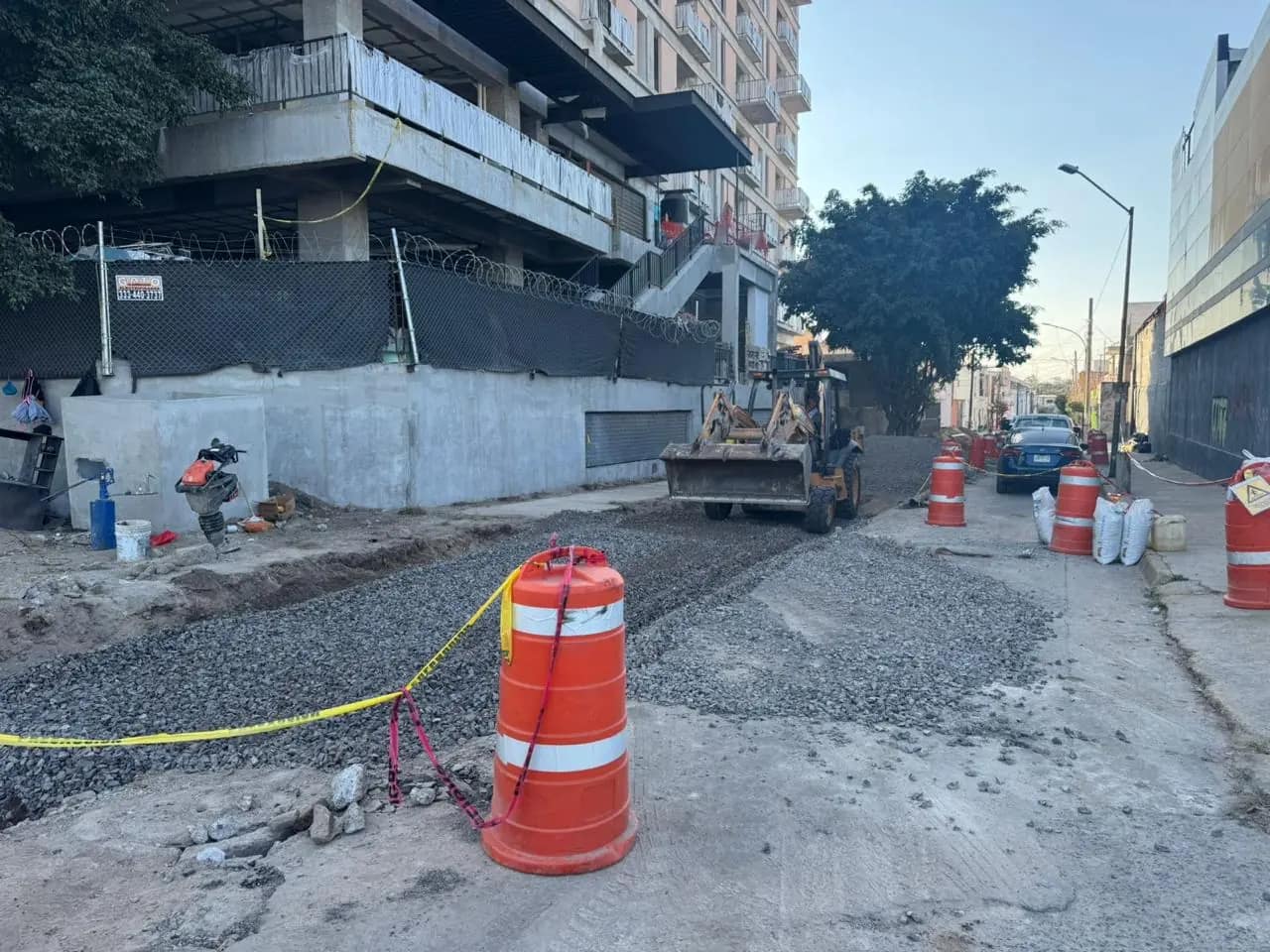 Backhoe backfilling a trench with gravel