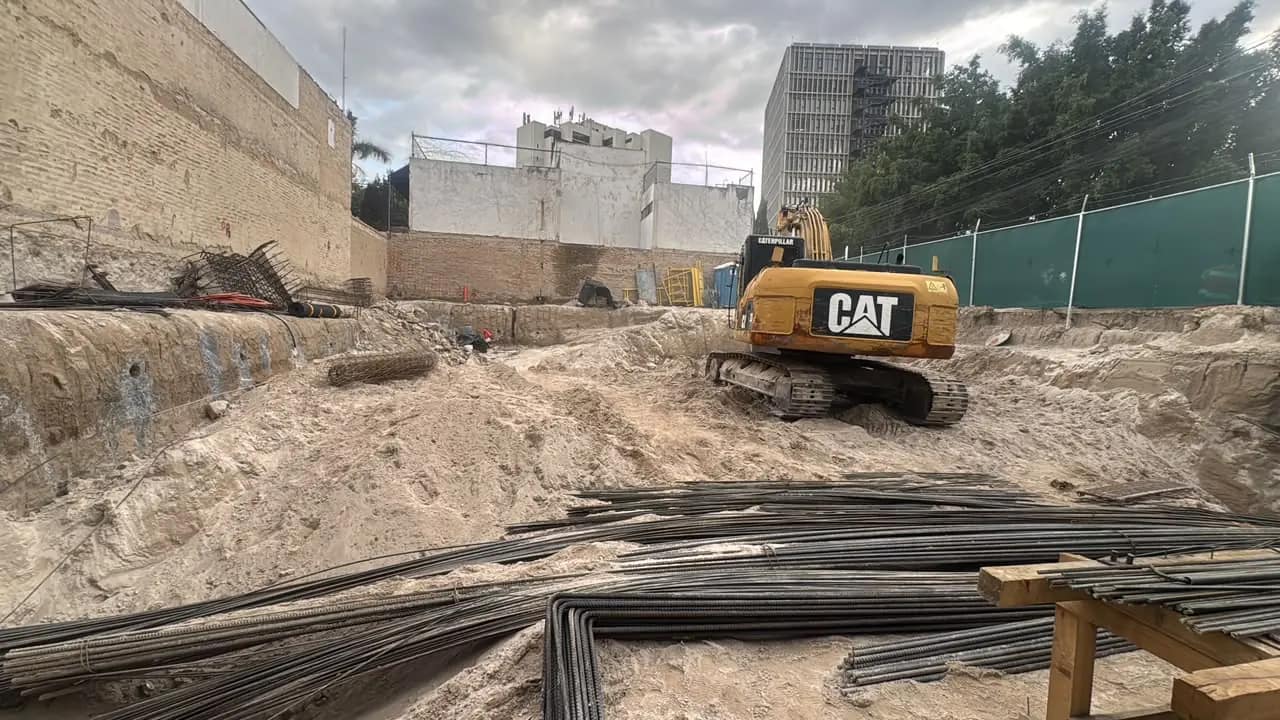 Excavadora CAT en excavación profunda urbana con malla perimetral